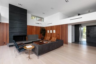 The entry foyer makes use of leather-finish hematite while honed basaltina slabs on the fireplace add a luxe material accent. Custom milled machiche wood makes up the interior paneling and cabinetry as well as exterior fencing, decking, and siding. The floors are wide planks of white oak. 