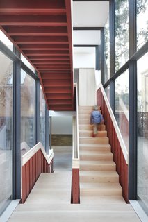 An exposed steel staircase in a glazed circulation link connects the two living wings.