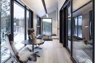 Light ash flooring and birch plywood walls create a light interior that contrasts the dark, charred exterior wood. Here in the lounge space, simple furniture such as the Scandia Chair by Hans Brattrud and a central pellet stove create a calm, inviting environment. A floor-to-ceiling window, facing north, is your best bet for seeing the Aurora Borealis. 