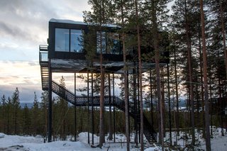 Guests ascend a staircase into the cabin, while a small lift carries up their luggage.
