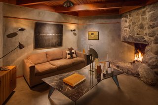 Find Seclusion in the City With This $2.5M Lloyd Wright Residence - Photo 3 of 7 - The den provides a cozy seat by the fire. The original wood beams of the ceilings have aged to a golden brown. To match the hue, Powell has stained the wood used for cabinets, doors, molding, a built-in bed, and wainscoting.