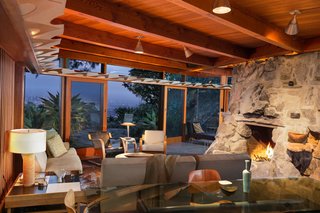 Find Seclusion in the City With This $2.5M Lloyd Wright Residence - Photo 5 of 7 - Another view of the living and dining area shows the stone fireplace and outdoor deck, which offers a commanding vista. A private wing extends from the common space and holds the bedrooms and bathrooms.