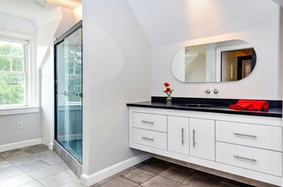 The main bathroom features a Zuma bathtub (not pictured) and Hansgrohe bath and shower fixtures. The flooring is Crossville porcelain tile, and the mirror was designed by Reed.