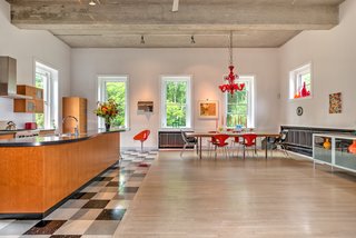 The first floor holds an integrated living room, dining room, and kitchen. When Reed and Blackburn bought the firehouse, the concrete floors were stained with oil from the firetrucks, so they laid stained white oak flooring. They also sandblasted the ceiling to its original concrete finish. A red Murano glass chandelier hangs over a vintage Danish dining table and Bernhardt Design Orbit Chairs. 