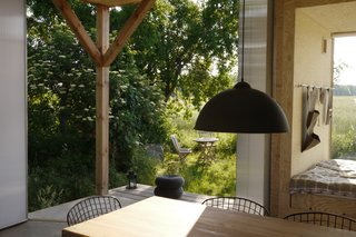 The three summer houses at Re:hof Rutenberg are nestled in blackthorn shrubs and enjoy idyllic meadow views. Summer house Salix, shown here, was designed by Peter Grundmann. A retractable screen opens up the space to a triangular porch.