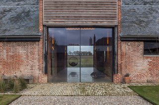 Two oversized glazed doors welcome guests into Church Hill Barn. "We wanted it to look like the barn doors were open," says Witt. Reclaimed brick paves the doorway.
