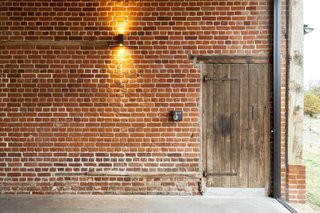 The lights are operated by original switch boxes. Beside it, a barn door leads to the three bedrooms.