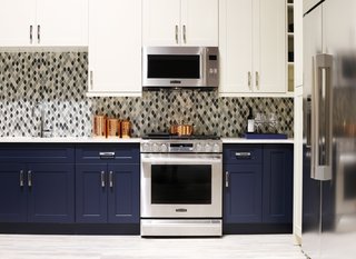 The Signature Kitchen Suite Smart Kitchen is outfitted with navy and ivory cabinets by Green Forest Cabinetry and a glass tile mosaic backsplash. For Fuller, who comes from a product design background, the "smart thinking" of the brand's designs put them ahead of the curve. For example, the Gas Slide-In Oven Range above has an Easy Swivel Handle that is easier and safer to operate, and the capacious refrigerator benefits from a SmartSpace System ice dispenser that maximizes storage space.