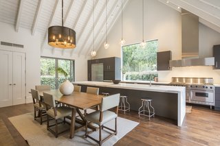 The oversized kitchen island is outfitted with a marble countertop. Boasting upscale, stainless steel appliances, plenty of workspace, and framed views of the surrounding greenery, the kitchen is undoubtedly one of the most versatile and functional rooms in the house. Another fireplace, just out of frame, creates a cozy atmosphere for the dining room.