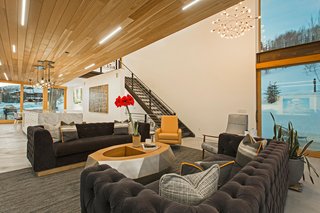 A Plunging Roof Carves Out Space in This Park City Home Offered at $2.4M - Photo 2 of 9 - Mullin discovered the Cirrus Linear LED lights in the red cedar wood ceiling at Dwell on Design in Los Angeles in 2015. Cold-rolled steel stairs lead to the upper level and add a touch of industrialism to the space. Adjacent to the living room is a large outdoor balcony, accessible through disappearing sliding glass doors.