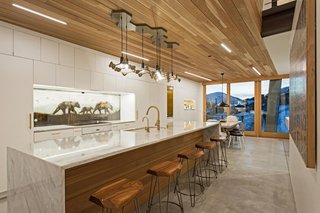 A Plunging Roof Carves Out Space in This Park City Home Offered at $2.4M - Photo 4 of 9 - A chandelier by artist Joe Norman provides a dramatic accent to the kitchen and dining areas. The backsplash was a commission by the artist KOLABS, part of Mullin's wife's gallery.