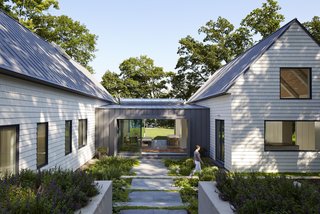 Where the New Buffalo Residence now stands on a wooded lot by the shores of Lake Michigan, there used to be a serpentine ranch house with perplexingly small windows, none of which pointed toward the water. The homeowners had used it as a vacation retreat for over 30 years before an expanding family—and guest list—led them to approach architecture firm Booth Hansen for a fresh design. "They wanted to feel the lake from every room," says principal Trina Sandschafer. "They wanted the house to breathe and have a connection between the indoors and the outdoors."