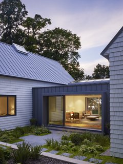 Cabins and Connectors Form a Family’s Lake Michigan Retreat - Photo 1 of 6 - A lushly landscaped bluestone terrace leads guests to the dining porch, which benefits from two LaCantina Multi Slide Door systems that measure 18 feet wide and nine feet tall.