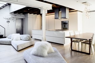 A Rooftop Addition on a 19th-Century Building Suits a Growing Family’s Needs - Photo 2 of 9 - The minimalist, open kitchen was built into freestanding millwork walls. Valgora strove to layer design elements from the 19th, 20th, and 21st centuries. "Old growth wooden beams and angled timber columns from 1869 are exposed with riveted steel columns and tangles of pipes and infrastructure from the 1920s conversion to a factory," he points out. A modular On the Rocks sofa by designer Francesco Binfare breaks up the space and transitions into the living room.