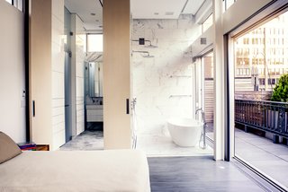A Rooftop Addition on a 19th-Century Building Suits a Growing Family’s Needs - Photo 6 of 9 - A marble wet room features a freestanding tub by Victoria and Albert and dual showers, while another shower on the terrace offers the option of washing outdoors. A 12-foot wooden door swings back to reveal a dressing room.