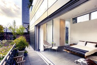A Rooftop Addition on a 19th-Century Building Suits a Growing Family’s Needs - Photo 5 of 9 - An expansive sliding glass door retracts into the zinc facade, opening up the master suite to a garden terrace with restored historic handrails. This echoes a 15-foot Corian wall that transforms a children's bedroom into an entertainment space, allowing flexibility and anticipating the time when the boys leave for college. 