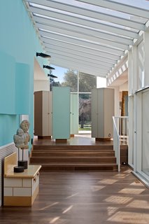 A glass atrium holds together four of the six pavilions that make up the home. Sottsass considered hallways to be unimaginative, preferring to create a flexible village of connected spaces. Above, an architectural light fixture grows organically from the blue wall. 