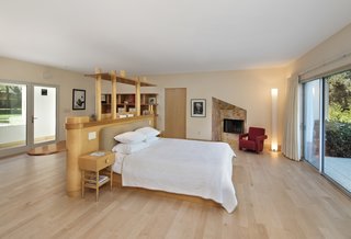 The master bedroom again defies convention by placing the pear wood and maple bed frame in the center of the room. A functional shelf activates the space behind it. Sliding glass doors beckon you onto a generous patio lined in blue tile. 