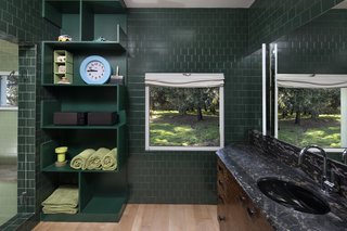The master bathroom forges a connection to the outdoors through dark, forest green tile.