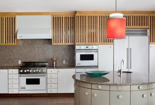 Oversized knobs add a whimsical touch to the kitchen, where a pendant designed by Johanna Grawunder—who worked with Sottsass in Milan—hangs over the circular island. White Viking appliances are integrated with the cabinetry.