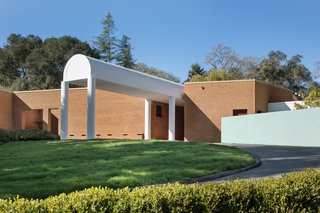 In defiance of the American tradition of placing the garage in front and putting cars on display, the Kelley Residence features a simple, brick wall facade that extends a white awning in welcome.
