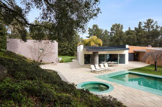 The pool and outdoor hot tub bounce green light off the roof hanging over the back terrace, creating a lush environment.