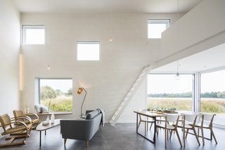 50 Modern Homes With Floor-to-Ceiling Windows - Photo 16 of 50 - When a photographer specializing in architectural work approached Studio Razavi Architecture for a summer home and studio, he envisioned a wood-clad construction on a small plot of land in Brittany, France. What he got was wildly different from his proposal—yet perfectly suited to his needs. The 1,130-square-foot home features a spacious main living areawith deliberately placed windows that frame the views. 
