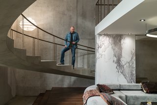 Here’s How Hollywood Builds a Malibu Dream Home—on a Vancouver Soundstage - Photo 3 of 10 - Above, Novotny surveys the set. The concrete walls and floors were created by pouring a quarter-inch layer of concrete over plywood. While marble is traditionally painted for film and television sets, Novotny took a different route to save time. After hunting down the perfect slab of Calacatta marble in a showroom, he hired a photographer to capture a high-resolution image that was then printed on sheets of white plastic by Astek Wallcovering in Los Angeles. 