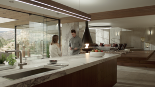 Here’s How Hollywood Builds a Malibu Dream Home—on a Vancouver Soundstage - Photo 8 of 10 - Kyle West and Megan Morrison, played by actress Christine Evangelista, have a conversation in the kitchen, which boasts walnut veneers. The glass panels that offer "oceanfront" views are each three feet wide, and are held with a strip of metal that allows the panel to spin—which comes in handy to manipulate reflections during filming.