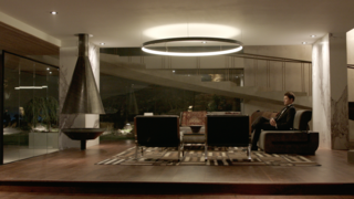 Here’s How Hollywood Builds a Malibu Dream Home—on a Vancouver Soundstage - Photo 5 of 10 - Kyle West, portrayed by actor Josh Henderson, sits in the living room of his home. Set decorator Renee Read outfitted the space with a custom couch that was originally made for the film Fifty Shades of Grey, the Nicholas Square Coffee Table by Restoration Hardware, the Nova Side Table by CB2 in collaboration with Kravitz Design, and Cammeo chairs by Natuzzi.