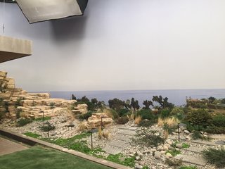 Here’s How Hollywood Builds a Malibu Dream Home—on a Vancouver Soundstage - Photo 9 of 10 - Novotny employed an "old-school theater trick" to give the impression of depth on the terrace, angling the lawn upward toward the photo backing to trick the eye. He also printed additional trees, glued them to plastic backing, and planted them at the end of the lawn. "You move your head, and the trees move a bit to give you a sense of perspective," he explains.