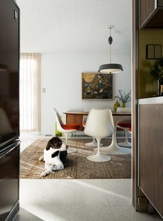 The homeowners love to host guests in the dining room, which features another set of Saarinen furniture. Banksy, a rescue lab and setter mix, takes a break from chasing toys up and down the hallways.