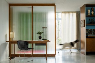 A Paul McCobb reeded glass panel provides a contemplative backdrop for a walnut Knoll writing desk and Bertoia Side Chair. "They feel like the soul of the house," says Coscarelli of the partitions. "They change constantly with the light." A Noguchi Number 9 Lamp is one of several original to the house.