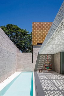 Located in São Paulo, Brazil, this outdoor space designed by Figueroa Arq employs both poured-in-place concrete and perforated concrete blocks to produce a strong contrast between the white-and-orange lattice of the blocks and the solid walls of the gray concrete. <span style="color: rgb(204, 204, 204); font-size: 13px;">Photo by Leonardo Finotti</span>