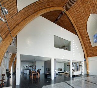 Ruud Visser Architecten designed House In A Church within an old wooden church from 1930 that rests along the river De Rotte in Rotterdam. The massive interior could fit an average of six family houses inside so they chose to build the house as a separate entity inside the church, leaving space to see the transition between the two.