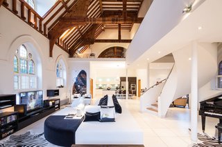 A Victorian-style church in London was converted by Gianna Camilotti Interiors into a modern home while keeping its historic charm. The outside may remain a traditional red brick, but the interior features white walls and floors, along with arched windows and wooden beams.