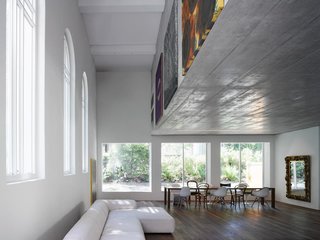 Located in Bern, Switzerland, the 1924 Luke Chapel went from rundown to two new modern homes by Morscher Architekten. To prevent covering the large church windows and to avoid adding support posts, the top apartment is suspended within a concrete box above. The box’s facade was the perfect place to display artwork.