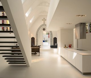 Zecc Architecten transformed this old Catholic church in Utrecht, The Netherlands into a single family home while managing to work with its original character. Church benches were reintroduced in the dining area as seating and the stained glass illuminates the mostly-white interior with colors and history.