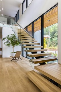 Set on top of a forested ridge separating downtown Portland and the suburban sprawl of Beaverton, OR, Wildwood by Giulietti / Schouten AIA Architects is a rural retreat and primary residence hidden within the metro area of the Pacific Northwest. The floating staircase features glass guardrails and white oak treads to match the hardwood floors. 