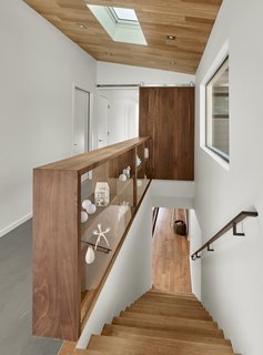 The solid walnut open shelves by furniture designer Matt Eastvold have a dual function: they act as a bannister around the second-floor stairwell and as a means for displaying personal items at this house by Knock Architecture + Design. Backed by glass, the shelf maintains visibility and lets in light while providing a safety barrier around the stair. 