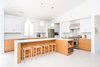 Modern home with Kitchen, Engineered Quartz Counter, White Cabinet, Wood Cabinet, Mosaic Tile Backsplashe, Pendant Lighting, Refrigerator, Range, Light Hardwood Floor, Range Hood, and Undermount Sink. The l-shaped island at the open kitchen encourages gathering while cooking. Photo 4 of A California Ranch Home, Reimagined