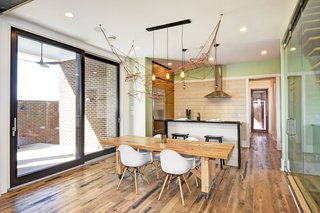 The bright and airy open floor plan features hardwood floors that are made from reclaimed wood from Kentucky horse farm fences. Shown is a reclaimed wood dining room table by Rework Collective and a biophilic chandelier from Honest Home by local Artist Leah Naomi. 