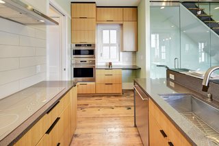 The sleek modern kitchen is compact, but has floor-to-ceiling storage cabinets neatly tucked away on either side providing ample storage. Locally made features include Monogram appliances, the porcelain tile, repurposed countertops, and FSC-certified, toxin-free custom cabinetry.