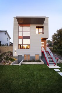 The structure features exterior materials that directly illustrate the dichotomy between Lawrenceville’s industrial heritage and Lola House’s residential nature. Here, corrugated metal siding is balanced with the warmth and softness of cedar siding, which was selected to emphasize the vertical circulation of the home. Red accents of cement board and steel bring a modern touch to the building’s exterior.