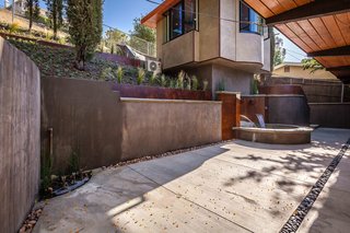 Detached tri-sided cantilevered hillside studio with adjoining spa. Terracing and spa surround prematurely rusted steel. 