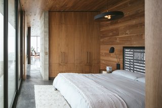 Black and white tones dominate this guesthouse on a Californian ranch. The color is also incorporated into this attractive black pendant with exposed bulbs, which complements the ebonized oak headboard.