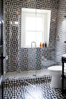 Monochrome tiles define the shape of this transparent bathroom shower. Designer Stacy Zarin Goldberg of Breeze Giannasio Interiors filled this space with thick visual texture and functional designation between the shower floor and the rest of the room.