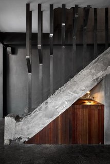 9 Unique Stair Railings - Photo 5 of 9 - While most stairs have continuous railings that allow your hand to slide up the railing as you ascend, vertical steel fins act as a spatial divider between upper and lower floors in this cafe in South Korea. The unfinished steel railing and the raw concrete stair emphasize the space's industrial feel.