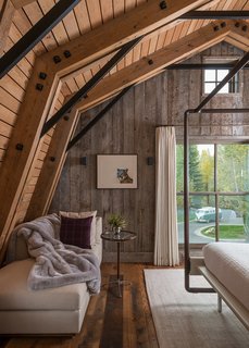 A Guest Barn in Jackson, Wyoming, Fuses Modern and Rustic Elements - Photo 2 of 7 - This living/bedroom space showcases neutral tones and shades of white to contrast the continued use of natural, treated wood surfaces.