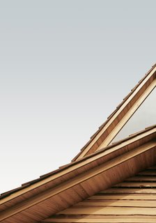 The stacked outer eaves set in warm cedar contrast the cool, neutral grays of the Yoshino sky.